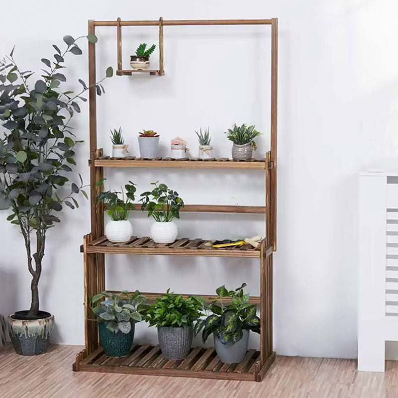 A tall, rustic wooden 5-tier plant shelf with a slatted bottom tray, styled with various potted green plants in white and gray pots against a white wall.