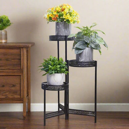 3-tier black metal plant stand displaying potted indoor flowers and green houseplants.