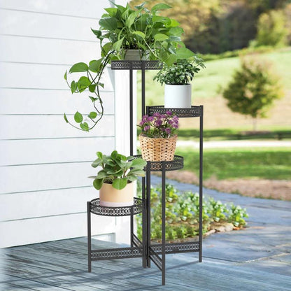 Multi-tiered black iron plant rack displaying various potted greenery and purple flowers outdoors.